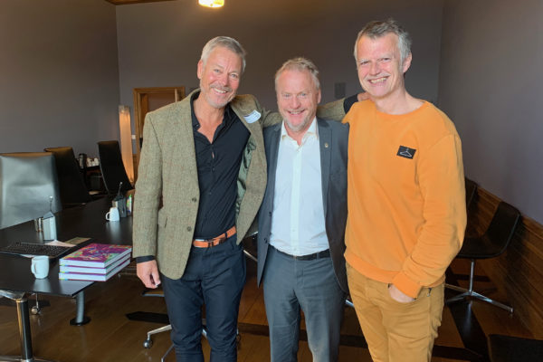 Geir Johnsen, leder for Ressursgruppe Boligutvikling, byrådsleder Raymond Johansen og OMA-sjef, Erling Fossen står og holder rundt hverandre og smiler til kamera. Raymond står i midten.